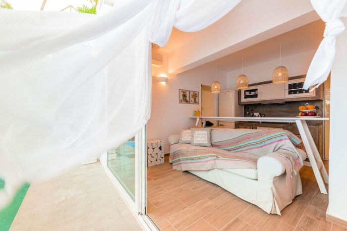 Stylish sofa in the living area of the 2 Bedroom Apartment with a view of the private pool at Kouros Home and Suites in Faliraki, Rhodes.